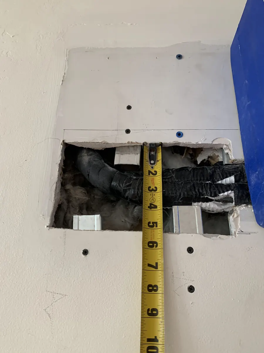 Drywall opening below mini-split prepared for patch installation