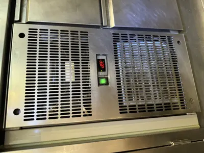 Commercial AC unit control panel with green indicator light and digital temperature display after servicing