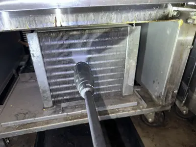 AC evaporator coil being cleaned with compressed air tool during maintenance service