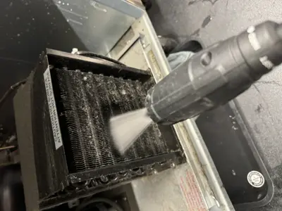 AC evaporator coil being pressure washed during maintenance cleaning service in NYC