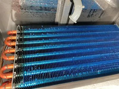 Clean blue AC evaporator coil fins with copper pipes after professional deep cleaning service