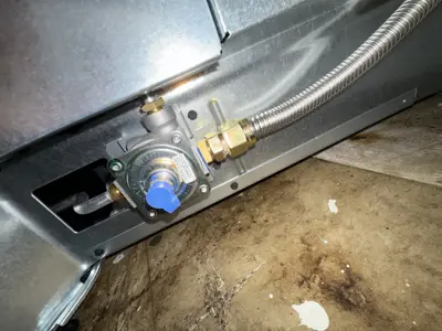 Gas regulator and flexible stainless steel connector installed on the base of a gas stove in NYC