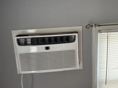 Completed window AC unit installation mounted flush in wall opening in NYC apartment