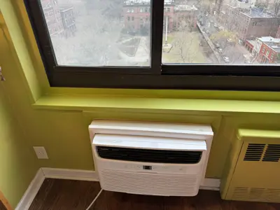 Window AC unit professionally installed in a NYC apartment with a city street view