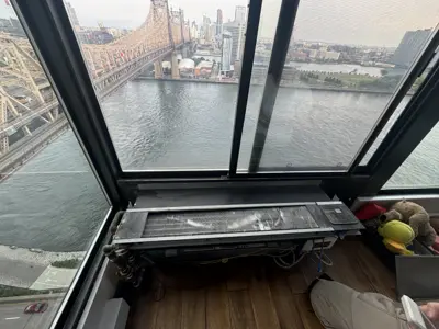 Floor-mounted AC unit being serviced in a high-rise NYC apartment with Queensboro Bridge view