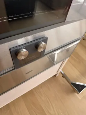Stainless steel built-in oven and warming drawer installed flush in modern NYC kitchen cabinetry