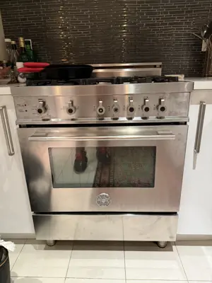 Stainless steel professional gas range installed in a modern NYC kitchen with white cabinets