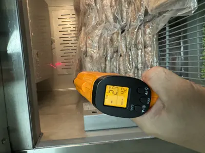 Technician using infrared thermometer to verify commercial freezer temperature after repair service in NYC