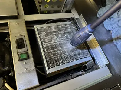 Technician pressure washing a commercial refrigeration condenser coil during appliance maintenance in NYC