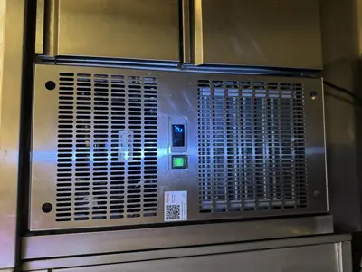 Close-up of commercial refrigerator condenser panel with status indicator lights after servicing in NYC