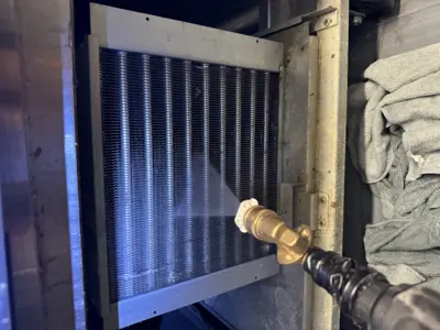 Technician pressure washing condenser coils on a commercial refrigeration unit during service in NYC