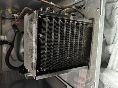 Heavily dust-clogged commercial refrigerator condenser coils before cleaning service in New York City
