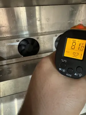 Technician using infrared thermometer to test appliance temperature readings during NYC repair service