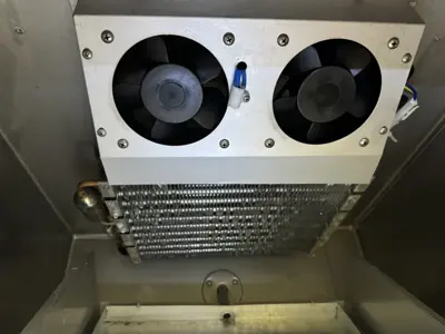 Interior evaporator coil and dual fans inside a commercial refrigeration unit serviced in NYC