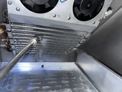 Pressure washing commercial refrigerator condenser coils and interior during deep cleaning service in NYC