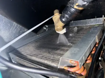 Technician pressure washing refrigerator condenser coils during deep cleaning service in NYC