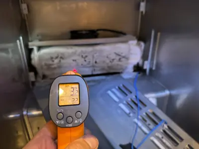 Technician using infrared thermometer to check freezer temperature during appliance diagnostics in NYC