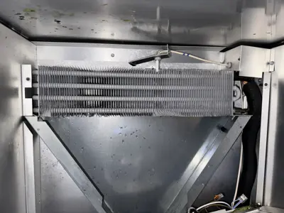 Clean evaporator coil and fan motor exposed inside commercial refrigerator after professional servicing