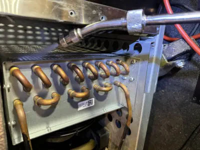 Internal copper evaporator coils of a commercial refrigerator being inspected and serviced by Repair ASAP technician