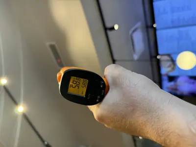 Technician using infrared thermometer to test refrigerator temperature during repair in NYC