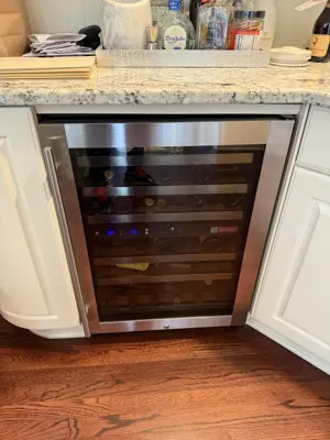 Stainless steel wine cooler installed under kitchen counter with granite countertop in NYC home