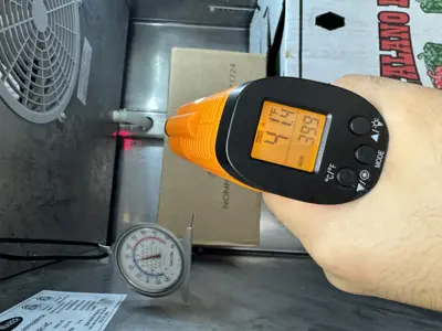 Infrared thermometer reading 39°F on commercial refrigerator after repair service in NYC