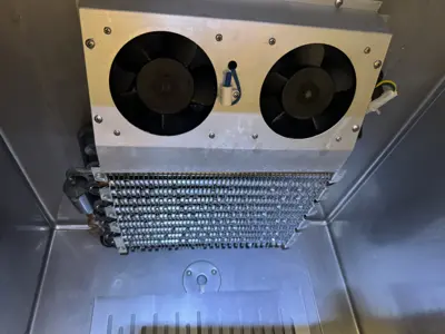 Clean commercial refrigerator interior with dual evaporator fans and defrost coil after professional servicing