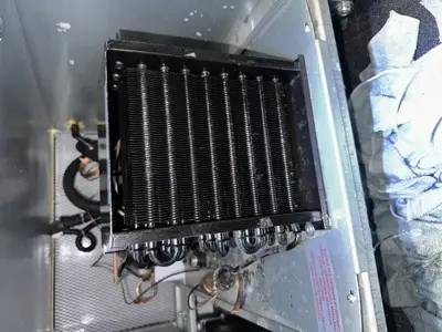 Refrigerator condenser coil unit removed and inspected during appliance repair in NYC