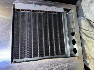 Close-up of commercial refrigerator evaporator coil unit removed for inspection or replacement in NYC