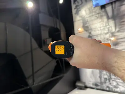 Technician using infrared thermometer to verify temperature readings on repaired commercial appliance in NYC