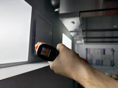 Handyman using infrared thermometer to check freezer compartment temperature after repair in NYC