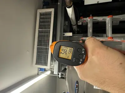 Technician using infrared thermometer to check temperature of commercial AC or refrigeration unit in NYC