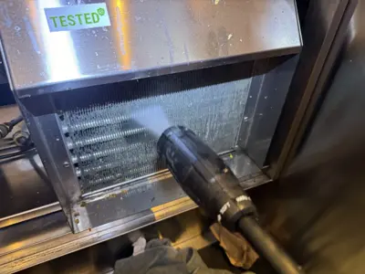 Pressure washing condenser coils on a tested commercial appliance unit during NYC service call