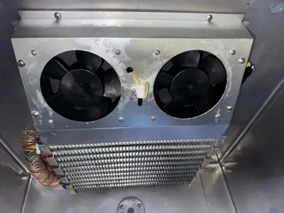 Dual evaporator fans and condenser coil inside a commercial refrigeration unit inspected by NYC handyman