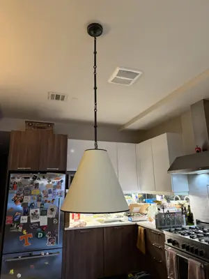 large pendant light fixture installed over kitchen island in nyc apartment with modern cabinetry