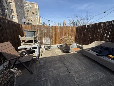 renovated nyc rooftop deck with bamboo privacy fencing, string lights, and outdoor furniture in manhattan