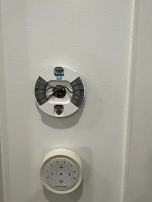 Nest smart thermostat installation in progress with wiring visible on white wall in NYC