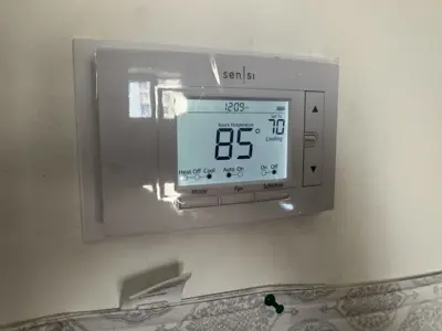 Sensi smart thermostat installed on wall showing 85°F room temperature and cooling mode active