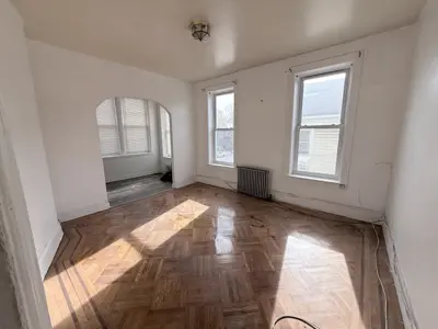 Restored herringbone parquet hardwood floor in NYC apartment living room with arch doorway