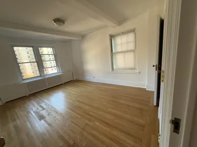 Bright NYC apartment room with freshly refinished hardwood floors and clean white painted walls