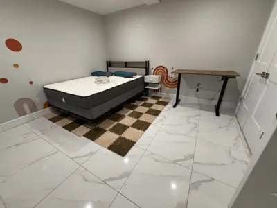 assembled bed frame with mattress and standing desk in a bright nyc bedroom with marble tile flooring