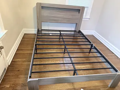 Bed frame assembly in progress showing metal support slats and wooden headboard in NYC bedroom