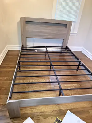 Bed frame assembly in progress with headboard and metal support slats in a NYC bedroom