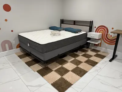 fully assembled bed frame with mattress and nightstand in a bright bedroom with marble tile floor