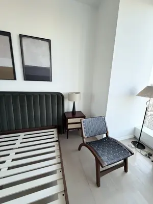 Assembled bed frame with headboard and accent chair in a modern NYC bedroom