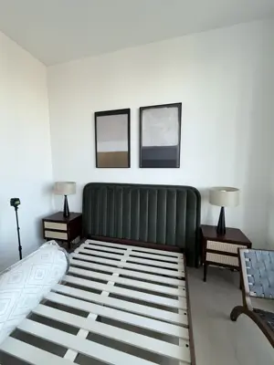 Fully assembled bed frame with upholstered headboard and nightstands in a clean NYC bedroom
