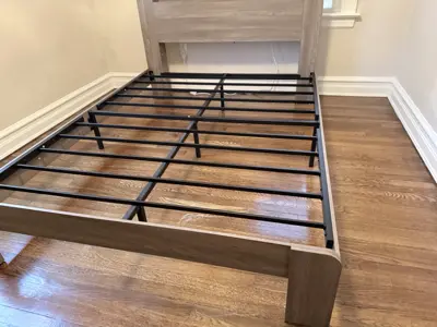 Bed frame assembly in progress showing metal slat support system on hardwood floor in NYC