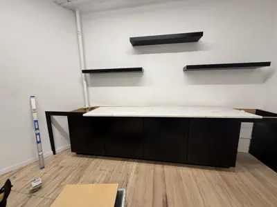 Assembled dark wood media console with marble top and floating wall shelves in NYC space