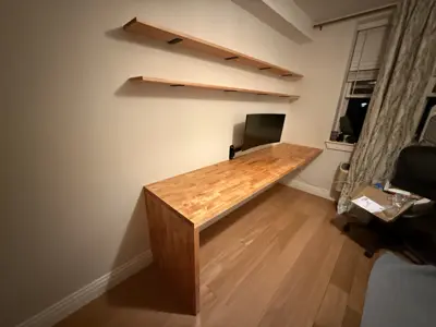 Custom wood desk and floating wall shelves installed in NYC apartment home office