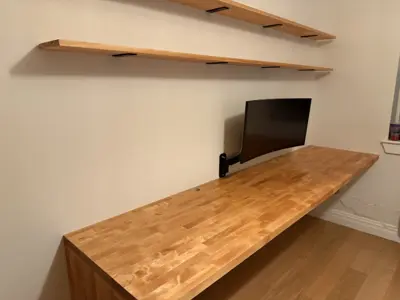 Butcher block desk and floating wall shelves with monitor arm installed in NYC home office